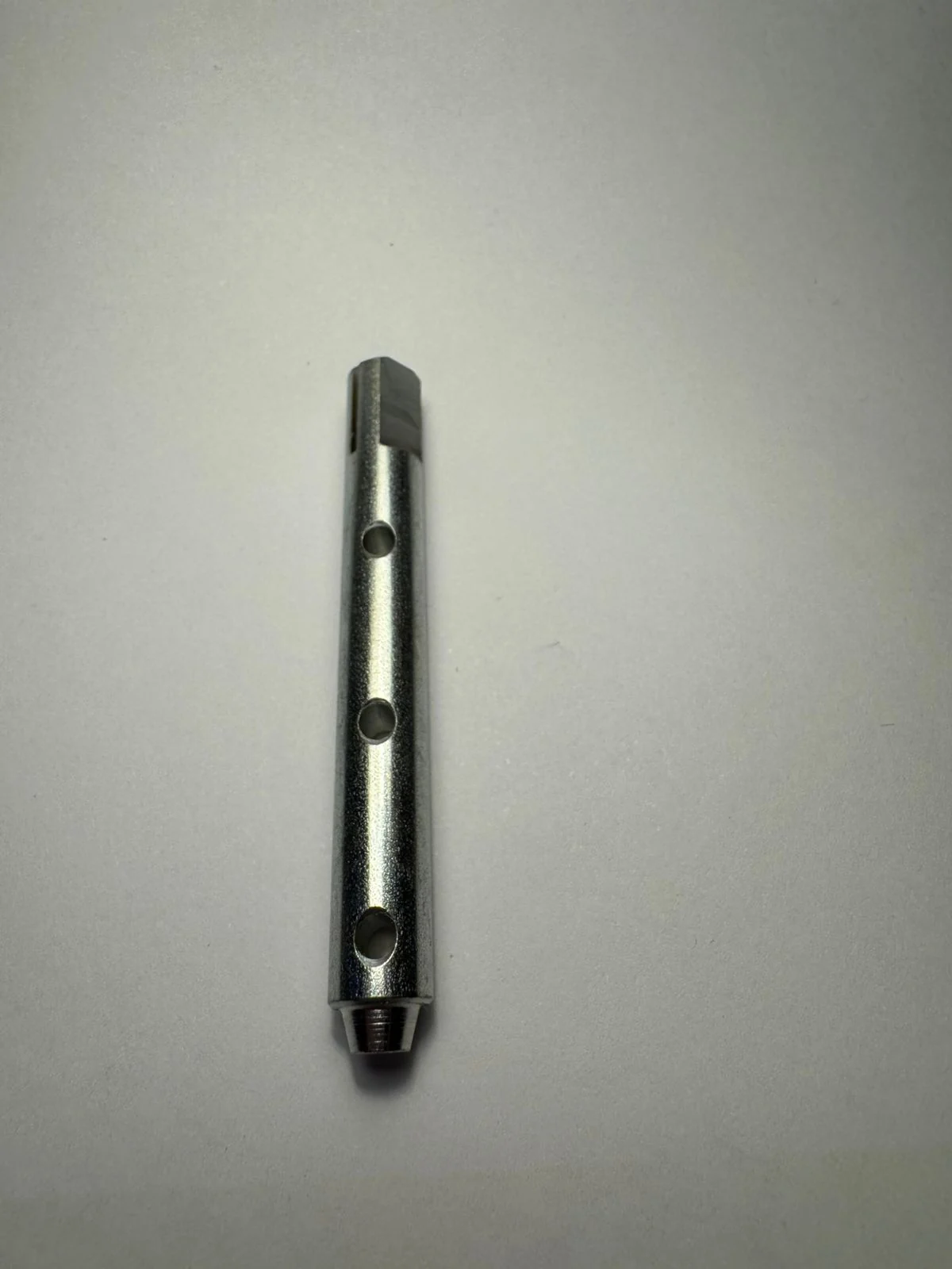 Eje largo con tres perforaciones transversales, extremo con cara plana y punta roscada